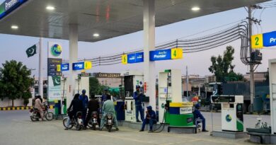 ‎A wide-angle, high-resolution shot of a modern PSO petrol station in Pakistan during twilight. The image shows several motorcyclists at the fuel pumps and attendants in blue uniforms. The station features "Euro 5 Premier" signage in blue and yellow, a large PSO pylon with a digital price board, and the Pakistani flag waving in the background. The scene is well-lit by overhead canopy lights against a soft evening sky.